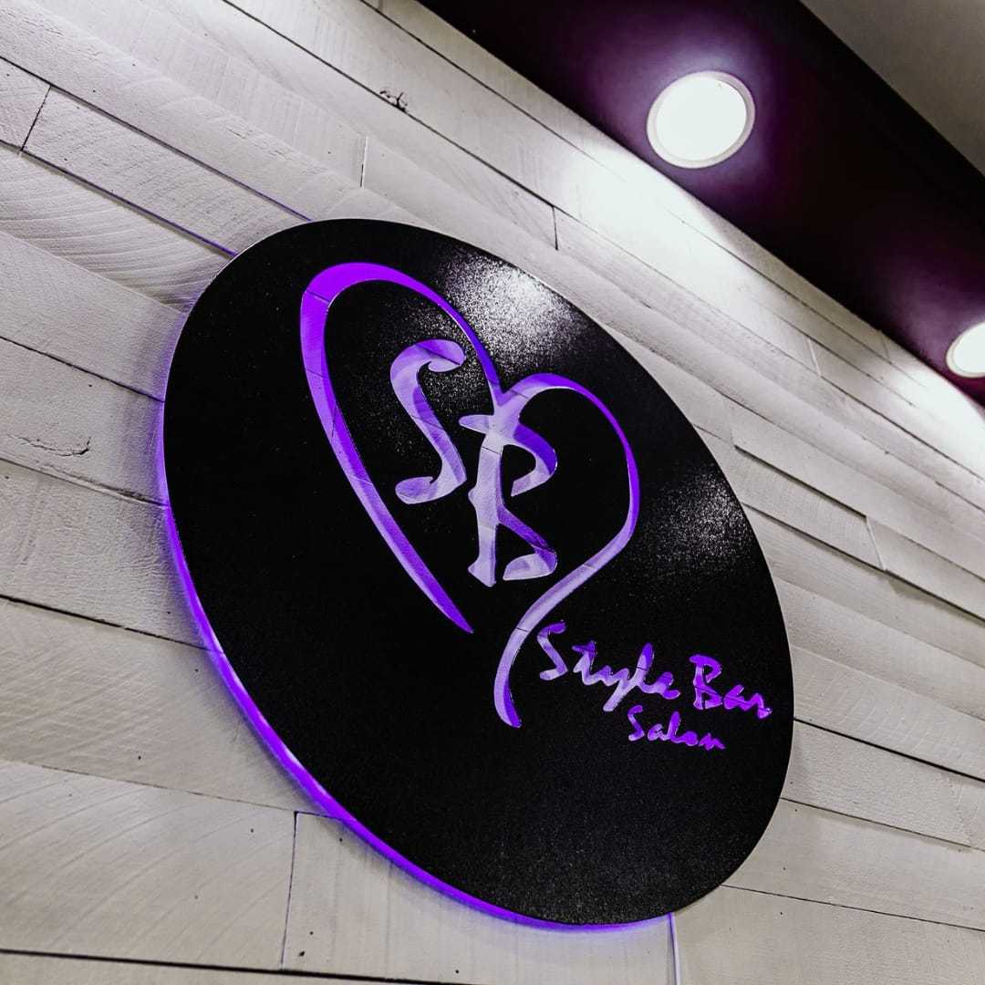 Stylish "SB" logo sign on a salon wall with purple lighting.