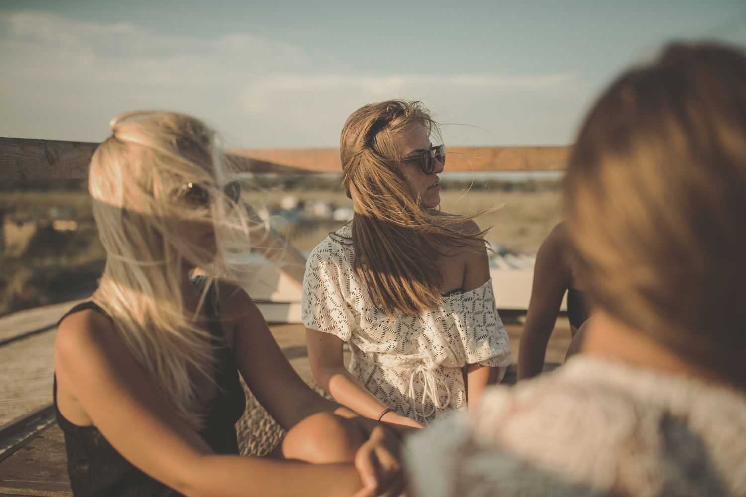 Group of friends enjoying a sunny day outdoors, hair blowing in the wind.